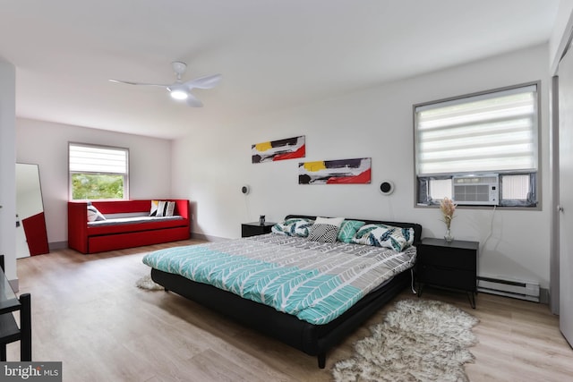 bedroom with ceiling fan, cooling unit, baseboard heating, and light hardwood / wood-style floors