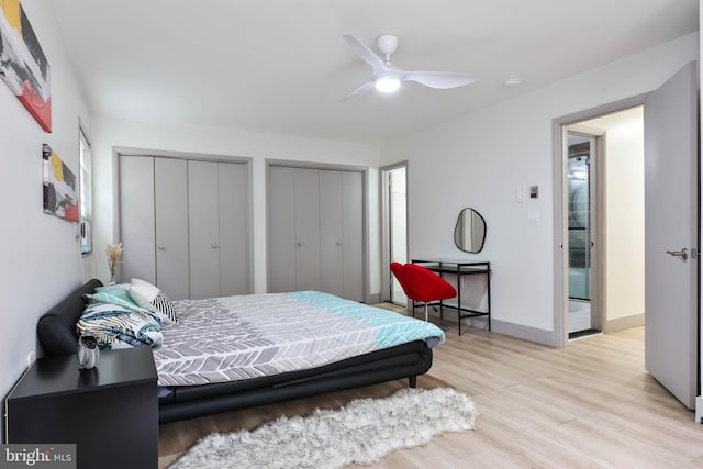 bedroom with light wood-type flooring, ceiling fan, and multiple closets