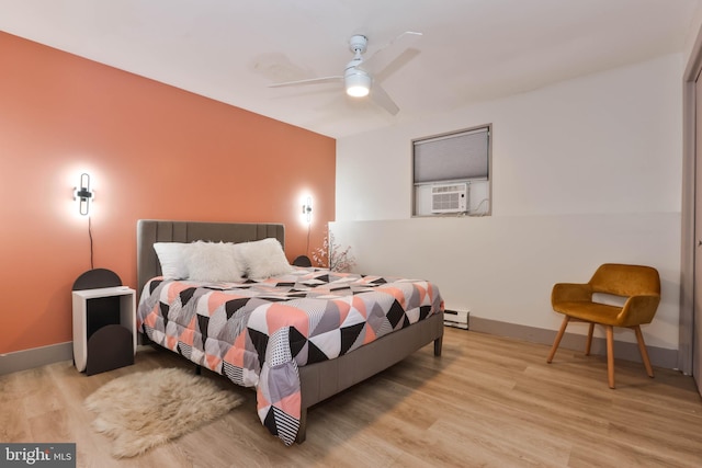 bedroom with cooling unit, light hardwood / wood-style floors, baseboard heating, and ceiling fan