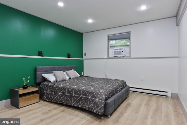 bedroom featuring cooling unit, baseboard heating, and light hardwood / wood-style flooring