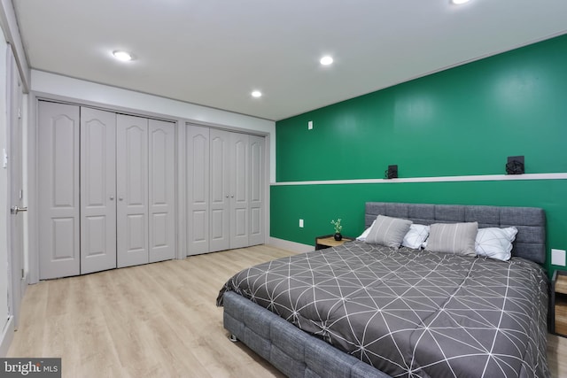 bedroom with two closets and hardwood / wood-style flooring