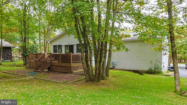 back of house featuring a lawn and a wooden deck