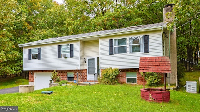 bi-level home featuring cooling unit, a garage, an outdoor fire pit, and a front yard