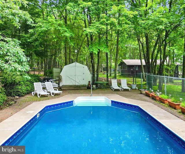 view of pool with a shed and a patio area