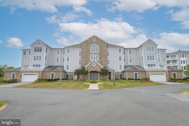 townhome / multi-family property featuring a garage and a front lawn