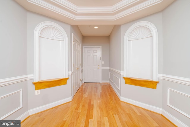 hallway with hardwood / wood-style flooring, a raised ceiling, and crown molding