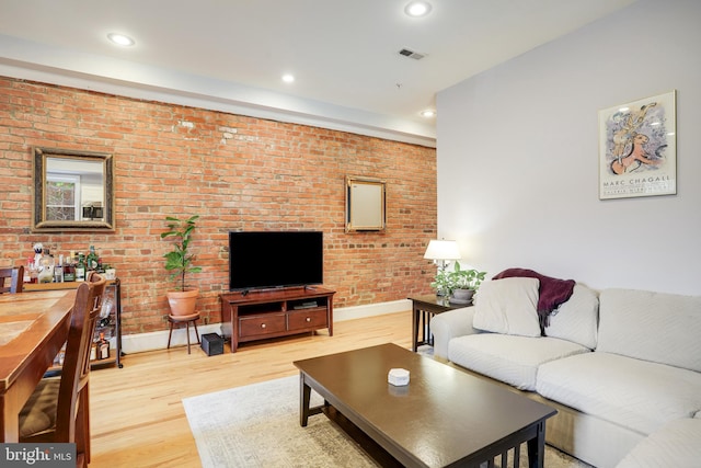 living room featuring brick wall and hardwood / wood-style floors