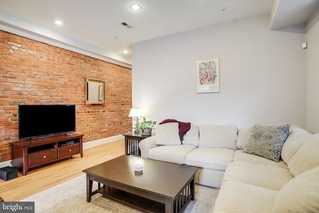 living room featuring brick wall and light wood-type flooring