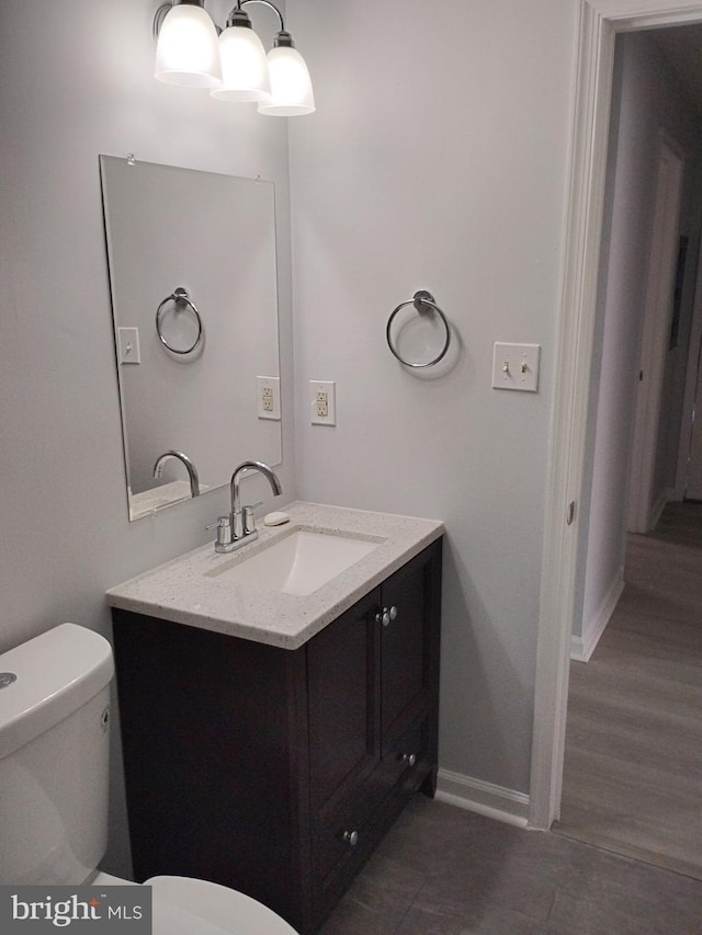 bathroom with vanity, toilet, and hardwood / wood-style floors