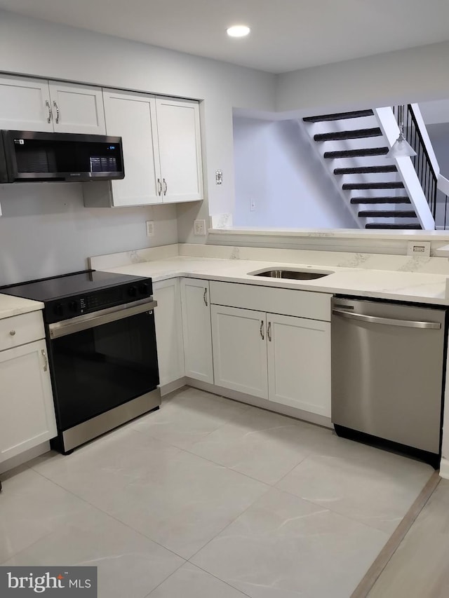 kitchen with stainless steel appliances, sink, light tile patterned floors, and white cabinetry