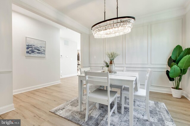 dining area with light hardwood / wood-style flooring, ornamental molding, and a chandelier