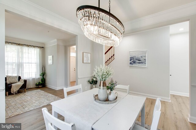 dining area with light hardwood / wood-style floors, ornamental molding, and a chandelier