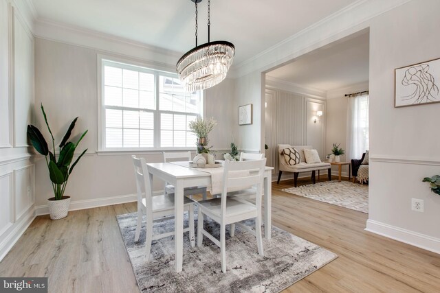 dining room featuring light hardwood / wood-style flooring, ornamental molding, and a notable chandelier