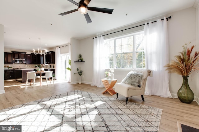 sitting room featuring light hardwood / wood-style floors, a healthy amount of sunlight, and ceiling fan with notable chandelier