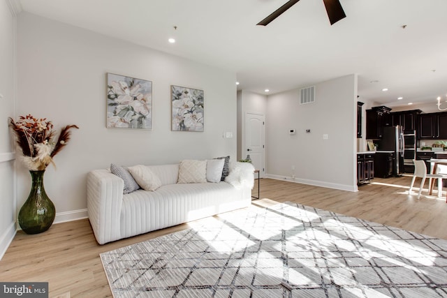 living room with light hardwood / wood-style flooring and ceiling fan