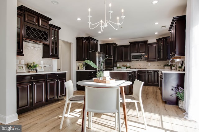 kitchen featuring backsplash, stainless steel appliances, light wood-type flooring, and a kitchen island