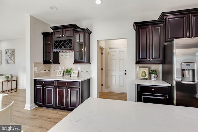 kitchen featuring light hardwood / wood-style flooring, decorative backsplash, dark brown cabinetry, and stainless steel fridge with ice dispenser