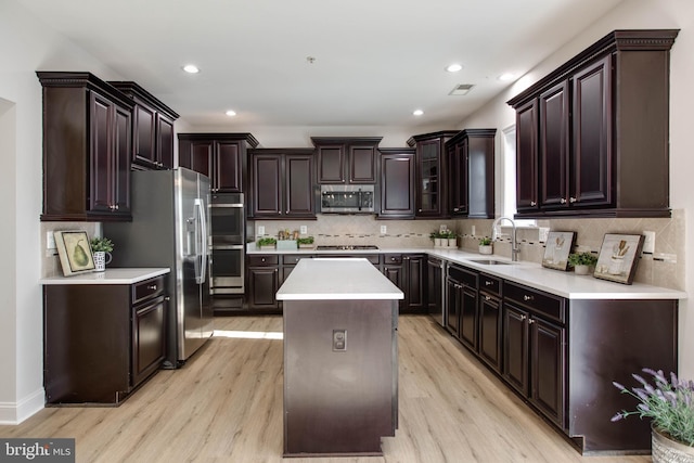 kitchen featuring appliances with stainless steel finishes, light hardwood / wood-style flooring, a center island, and sink