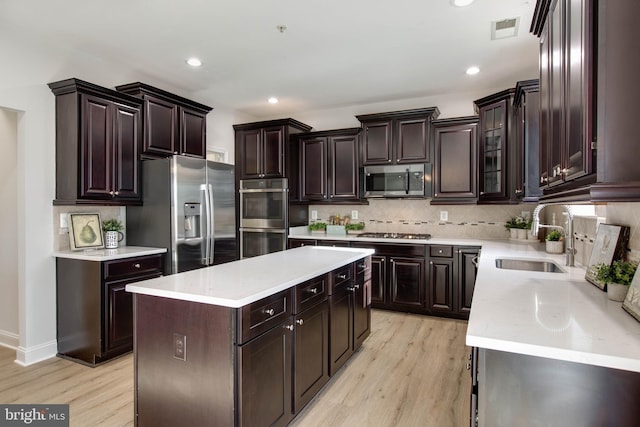 kitchen with light hardwood / wood-style floors, stainless steel appliances, sink, and a kitchen island