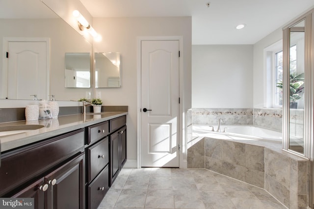 bathroom featuring vanity, a relaxing tiled tub, and tile patterned flooring