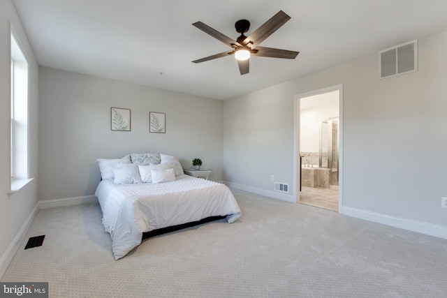 bedroom featuring ensuite bath, light colored carpet, and ceiling fan