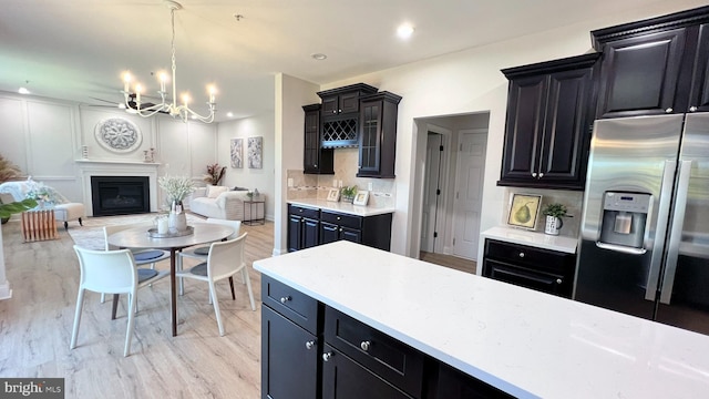 kitchen featuring hanging light fixtures, backsplash, light hardwood / wood-style flooring, a notable chandelier, and stainless steel refrigerator with ice dispenser