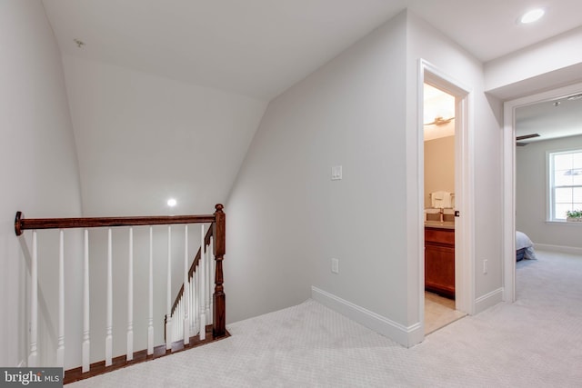 staircase featuring lofted ceiling, sink, and carpet flooring