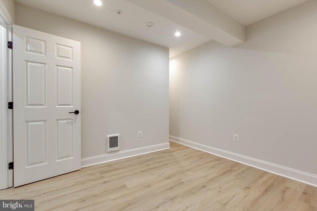 unfurnished room featuring light hardwood / wood-style floors and beamed ceiling