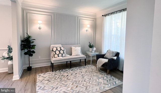 sitting room with crown molding and light wood-type flooring