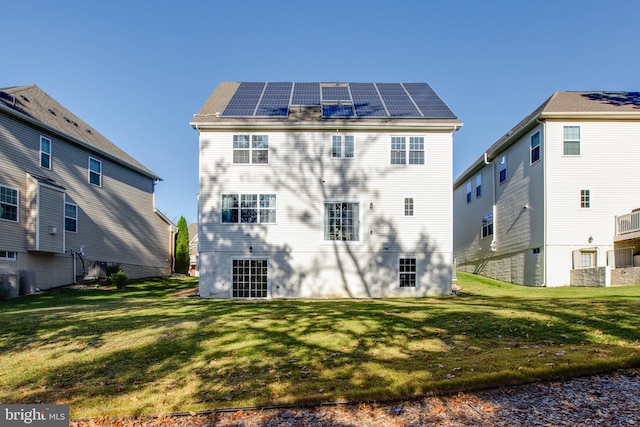 rear view of property with solar panels and a yard