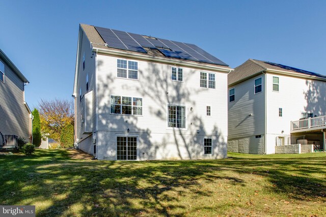 back of property with a lawn and solar panels