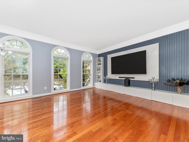 unfurnished living room with wood-type flooring and ornamental molding