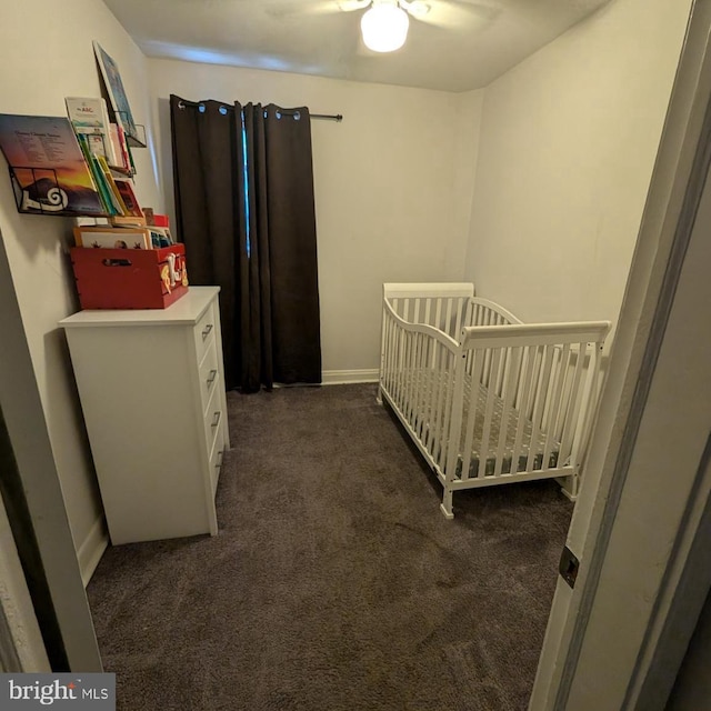 bedroom with ceiling fan, dark colored carpet, and a crib