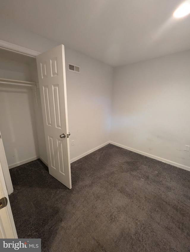 unfurnished bedroom with a closet and dark colored carpet