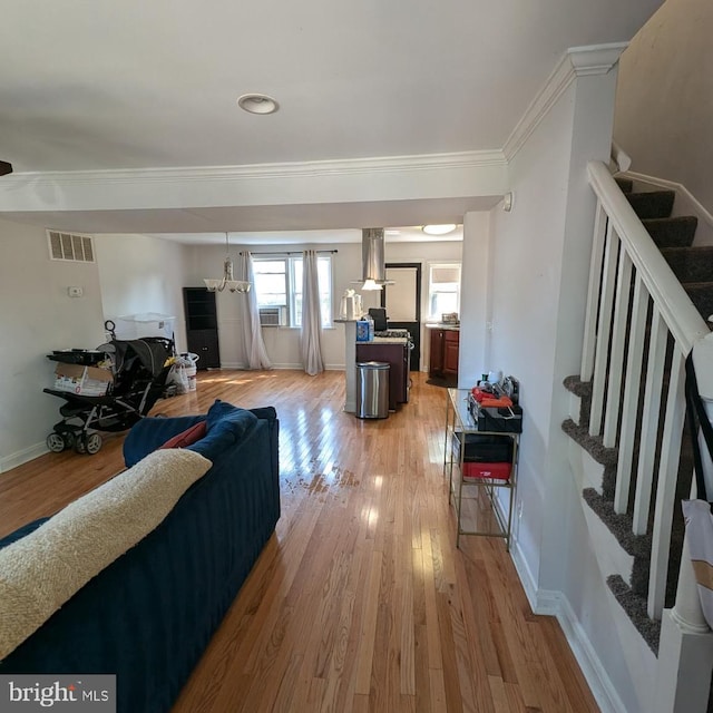 living room with an inviting chandelier, cooling unit, hardwood / wood-style flooring, and crown molding