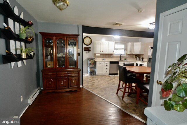 kitchen featuring backsplash, beam ceiling, stainless steel appliances, sink, and white cabinets