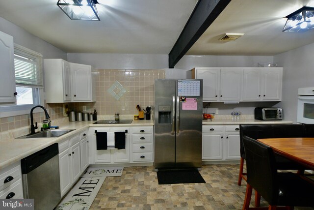 kitchen with white cabinets, white oven, sink, decorative backsplash, and stainless steel fridge with ice dispenser