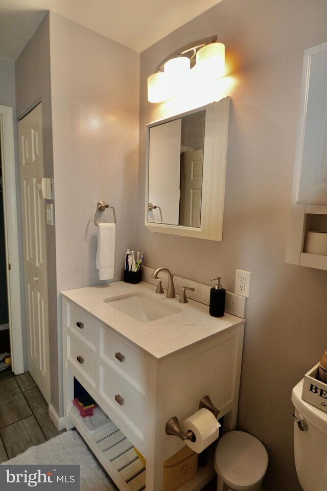 full bathroom featuring hardwood / wood-style floors, toilet, bath / shower combo with glass door, and vanity