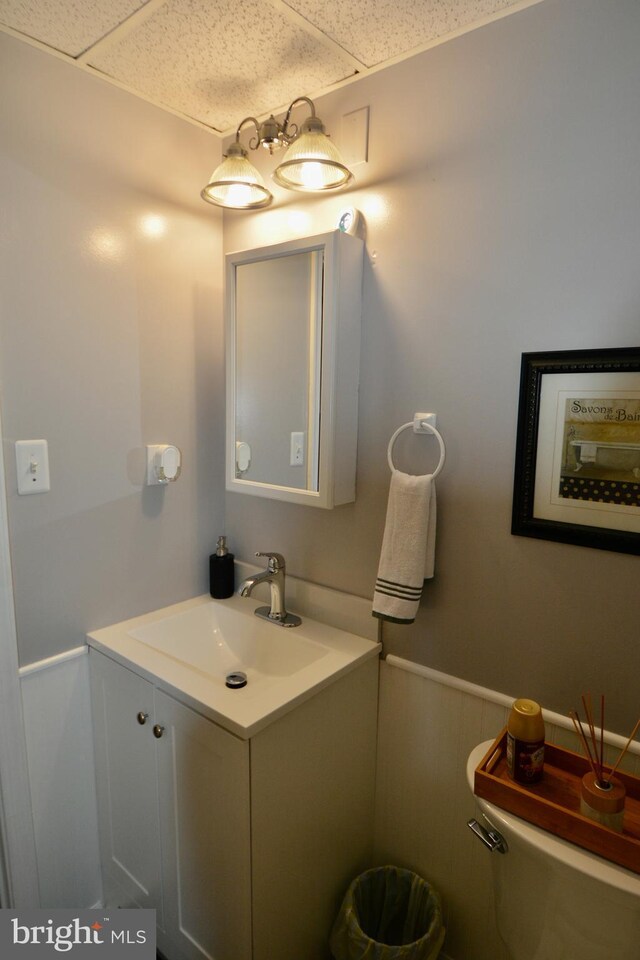 bathroom featuring vanity, toilet, hardwood / wood-style floors, and a drop ceiling