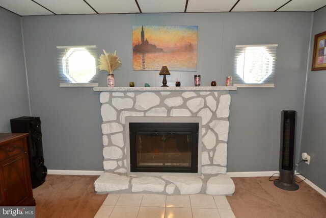 living room featuring carpet, ceiling fan, and a stone fireplace