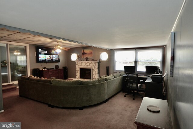 carpeted living room featuring ceiling fan and a drop ceiling