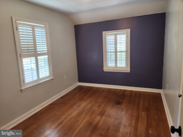 unfurnished room featuring lofted ceiling and dark wood-type flooring