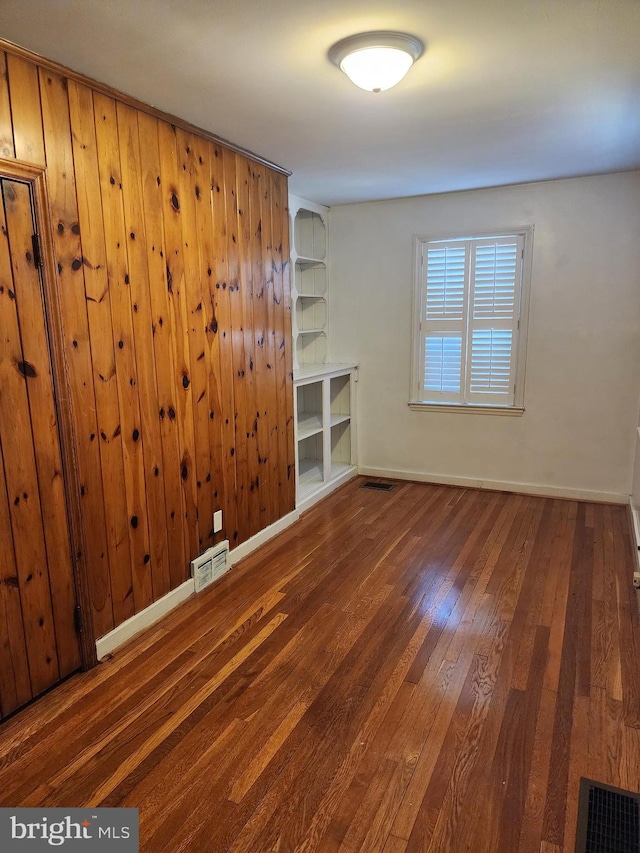 spare room featuring wooden walls and dark hardwood / wood-style floors