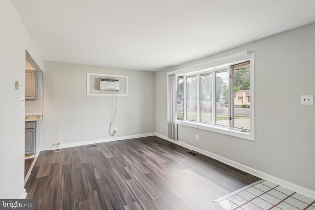 spare room featuring dark hardwood / wood-style flooring and a wall unit AC