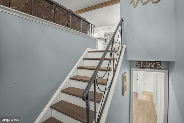 stairs featuring hardwood / wood-style flooring and beamed ceiling