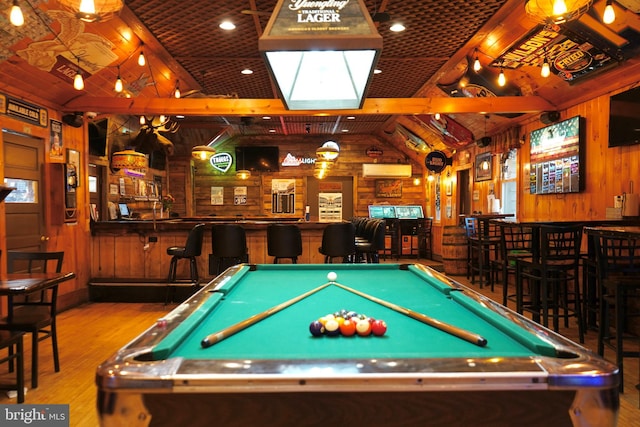 recreation room featuring pool table, light hardwood / wood-style floors, indoor bar, lofted ceiling, and wood walls