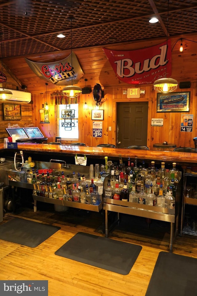 bar featuring a bar, wood finished floors, wood walls, and a wall mounted air conditioner