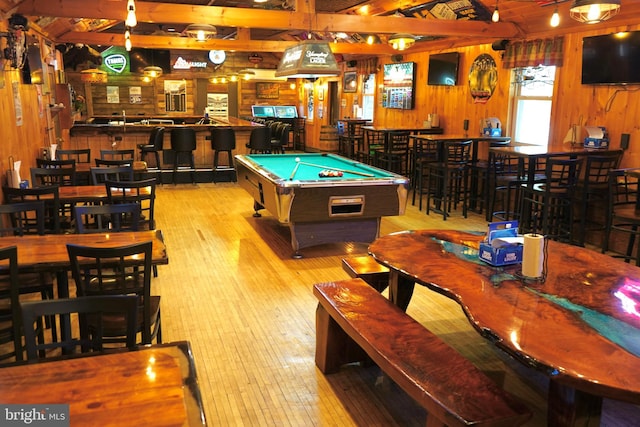 game room with billiards, hardwood / wood-style flooring, a community bar, and wood walls