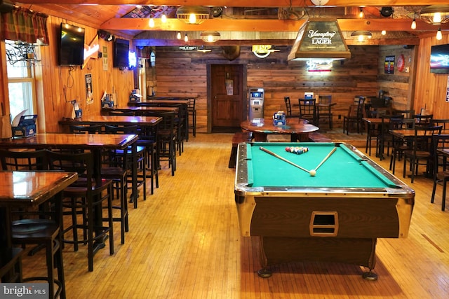 game room with light wood-type flooring, pool table, and wooden walls