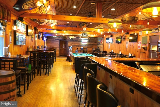 bar with billiards, hanging light fixtures, wood walls, and light wood-type flooring